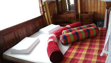 A bed with white linens, a colorful checkered bedspread, and rolled towels.