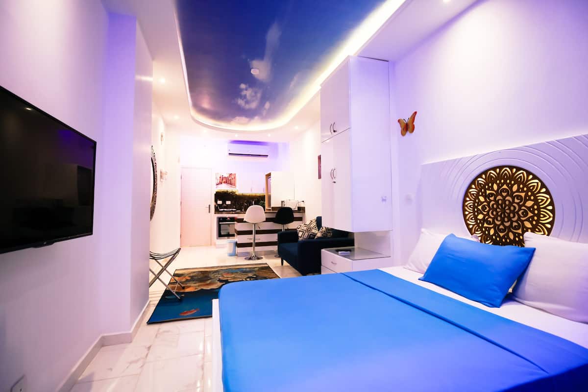 A modern bedroom with a large bed, a flat-screen TV, and a ceiling with a cloud design.