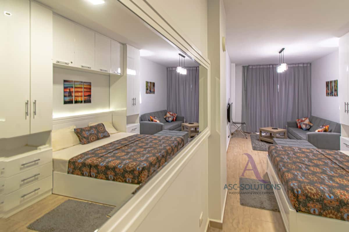 A modern bedroom with a bed, a desk, and a wardrobe.