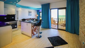 Una cocina moderna con barra, zona de comedor y balcón con cortinas azules.