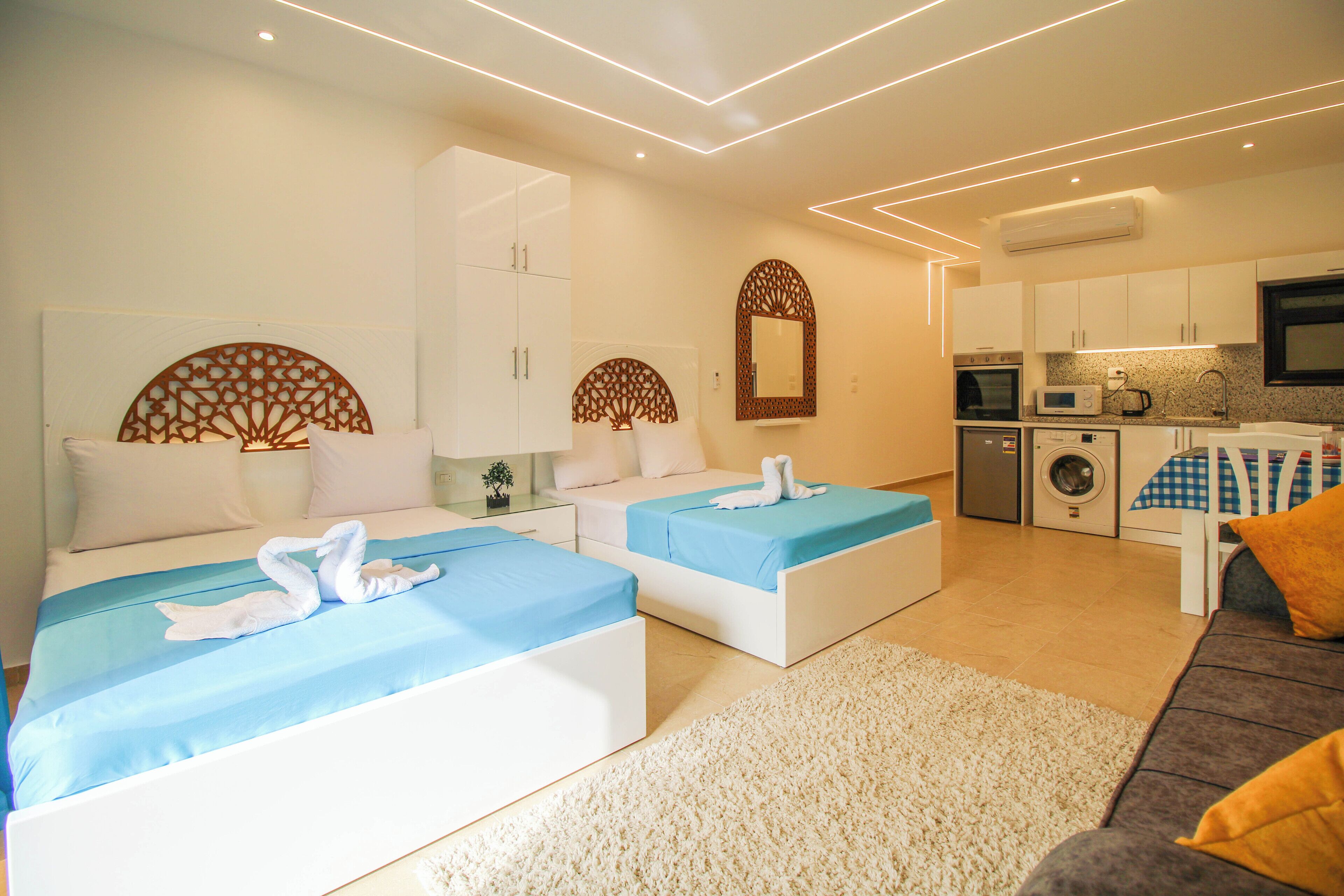 Une chambre d’hôtel moderne équipée de deux lits, d’un canapé, d’un coin cuisine et d’une salle de bain.