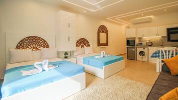Une chambre d’hôtel moderne équipée de deux lits, d’un canapé, d’un coin cuisine et d’une salle de bain.