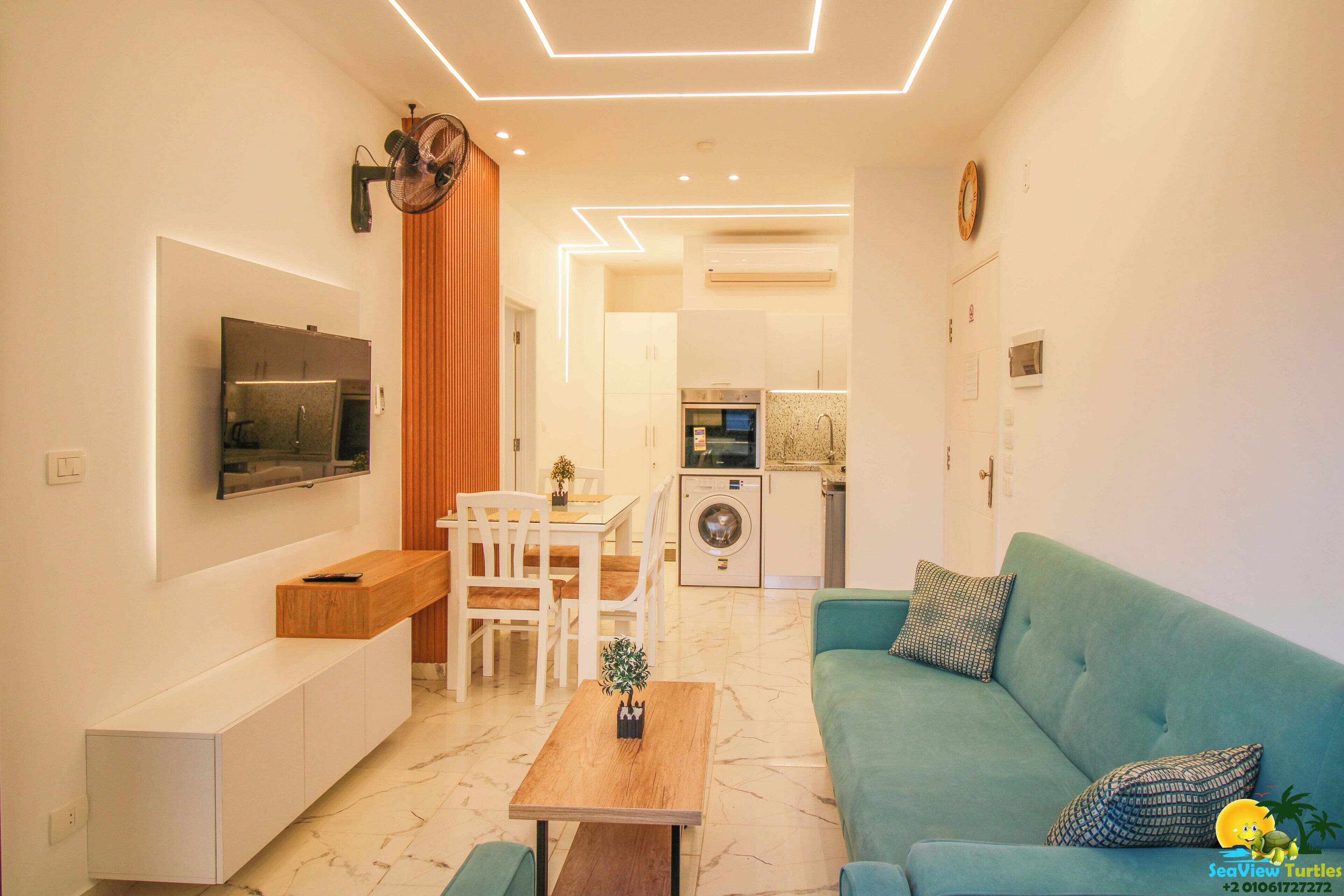 Un salon moderne avec un canapé, une table basse et un téléviseur fixé au mur.