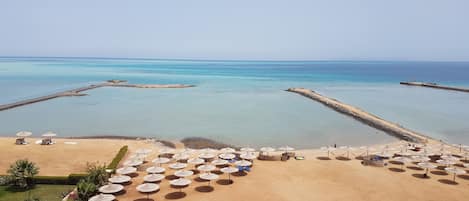 Een privéstrand, parasols, een strandbar