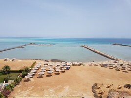 Un resort en la playa con múltiples sombrillas y sillas de descanso, una playa arenosa y vistas al mar.