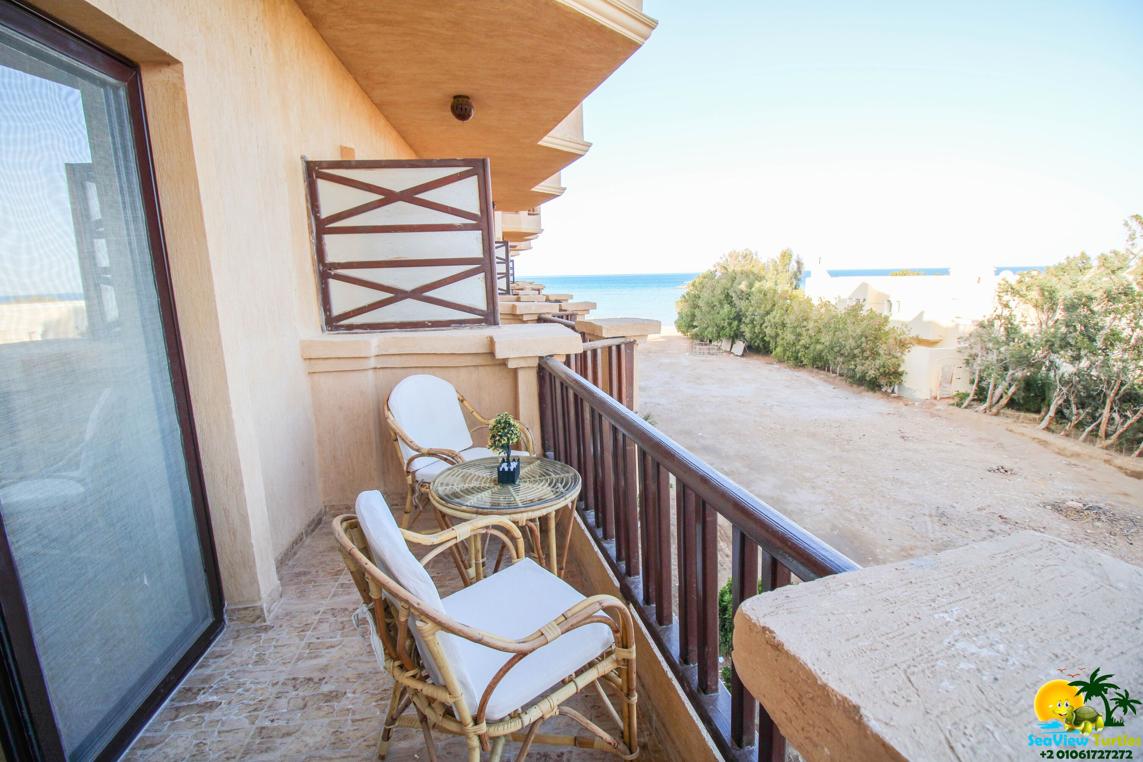 Ein Balkon mit Korbmöbeln, einem kleinen Tisch und Blick aufs Meer.