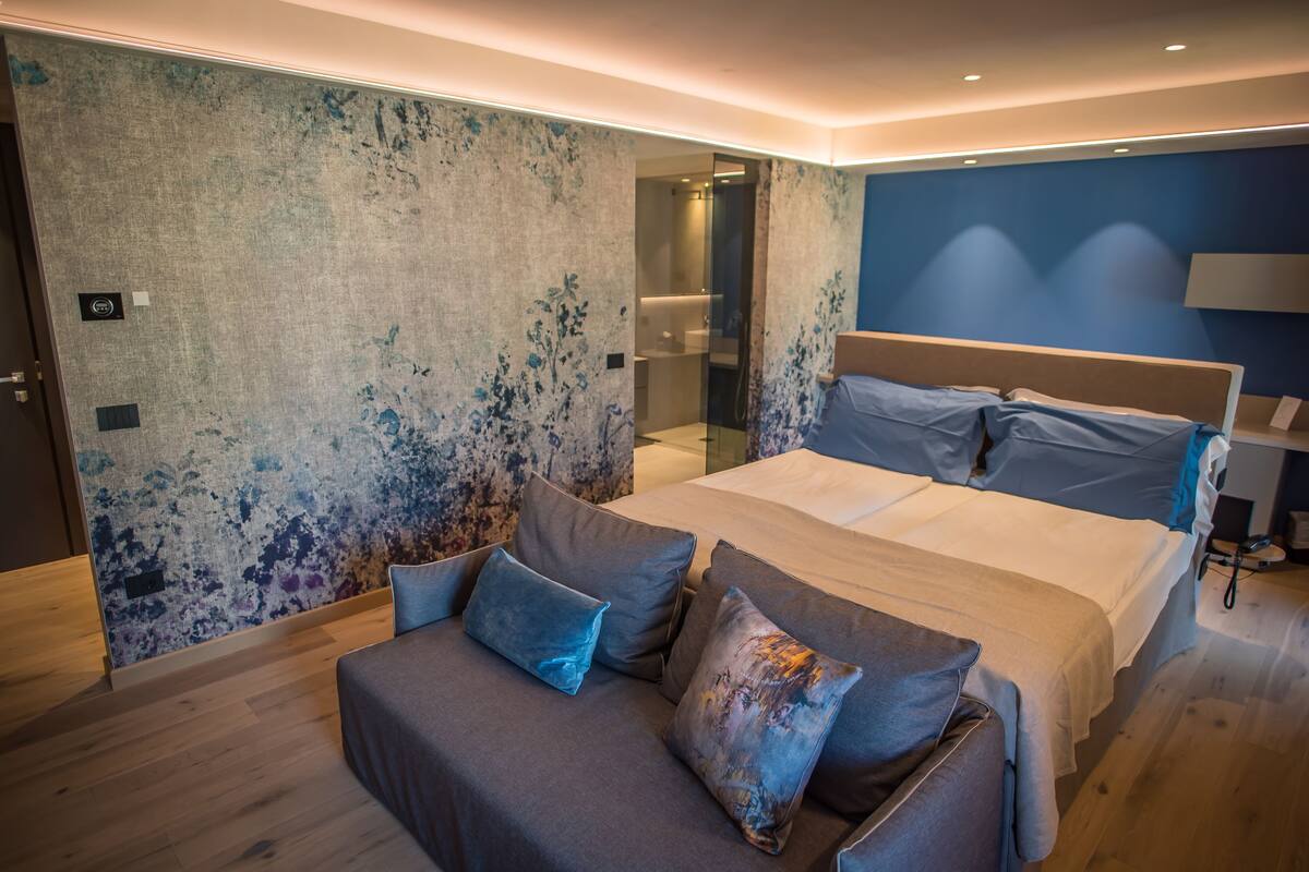 Un dormitorio moderno con una cama grande, un sofá y una zona de ducha.