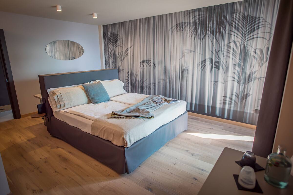 Un dormitorio moderno con una cama grande, una mesita de noche y una pared con un diseño de plantas verticales.