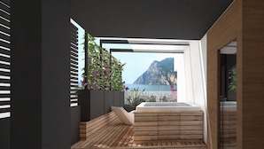 A modern bathroom with a wooden floor, a built-in bathtub, and a view of a mountainous landscape. - Hotel Villa Enrica (Riva del Garda)