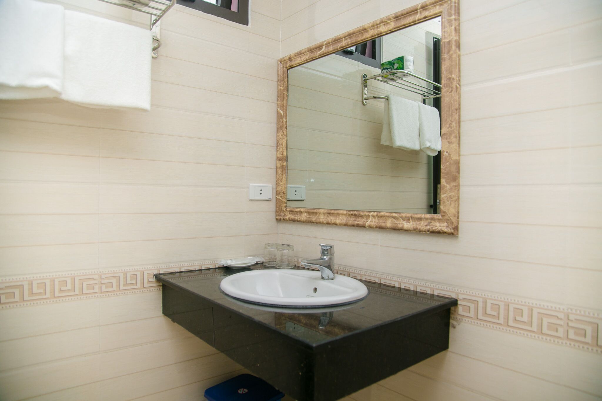 A bathroom with a marble sink, a mirror with a gold frame, and a towel rack.