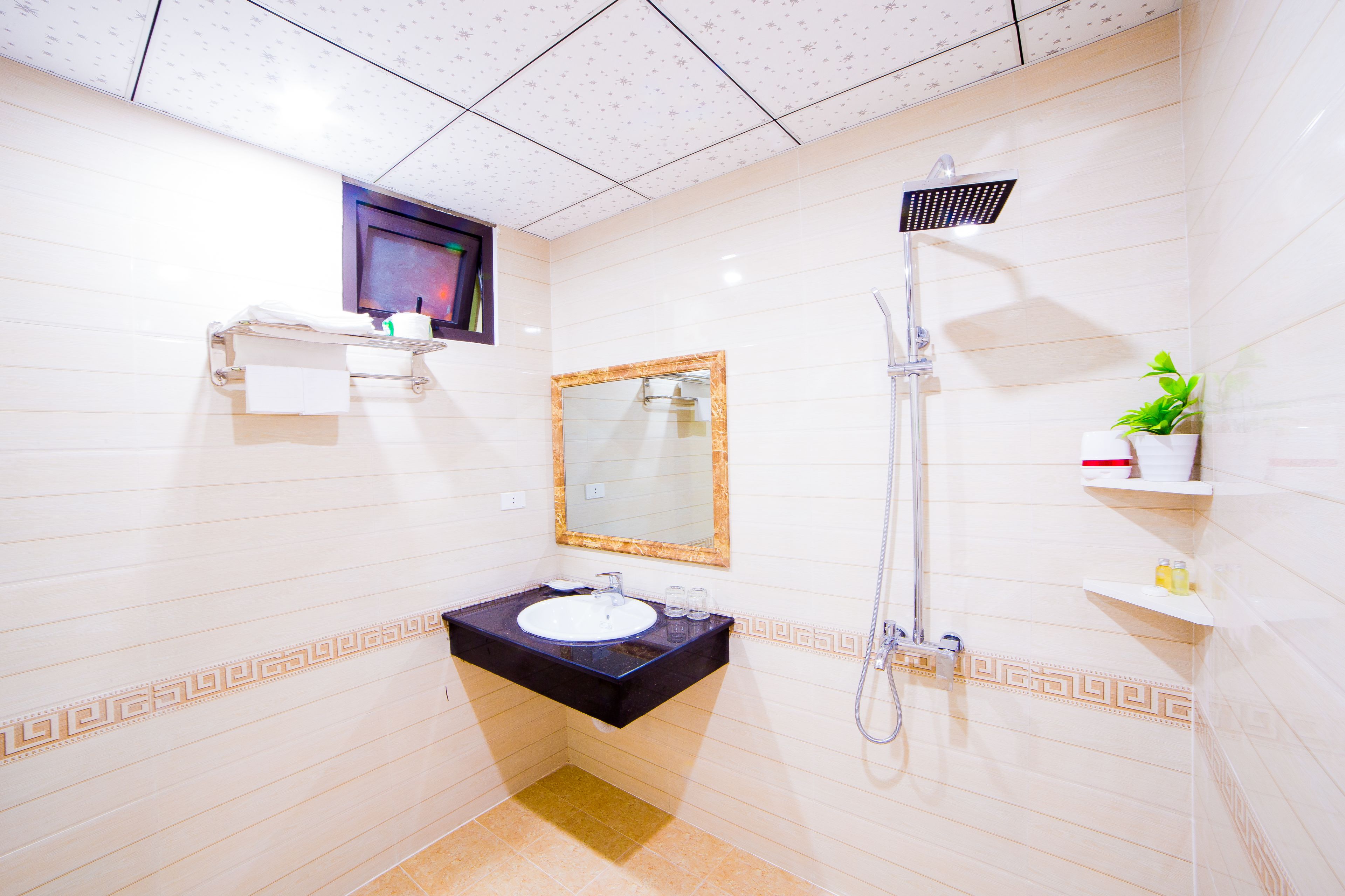 A bathroom with a sink, mirror, shower, and a small shelf with toiletries.