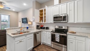 A modern kitchen with white cabinetry, stainless steel appliances, and a granite countertop. - Experience a First Class Stay - 2 BDRM (Humble)