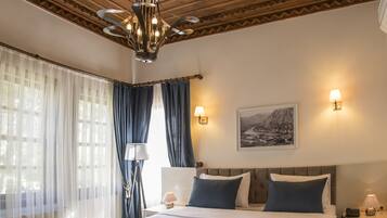 Relax in a spacious room with a large bed, bedside lamps, and a wall-mounted lamp, set against a classic ceiling with a skylight.