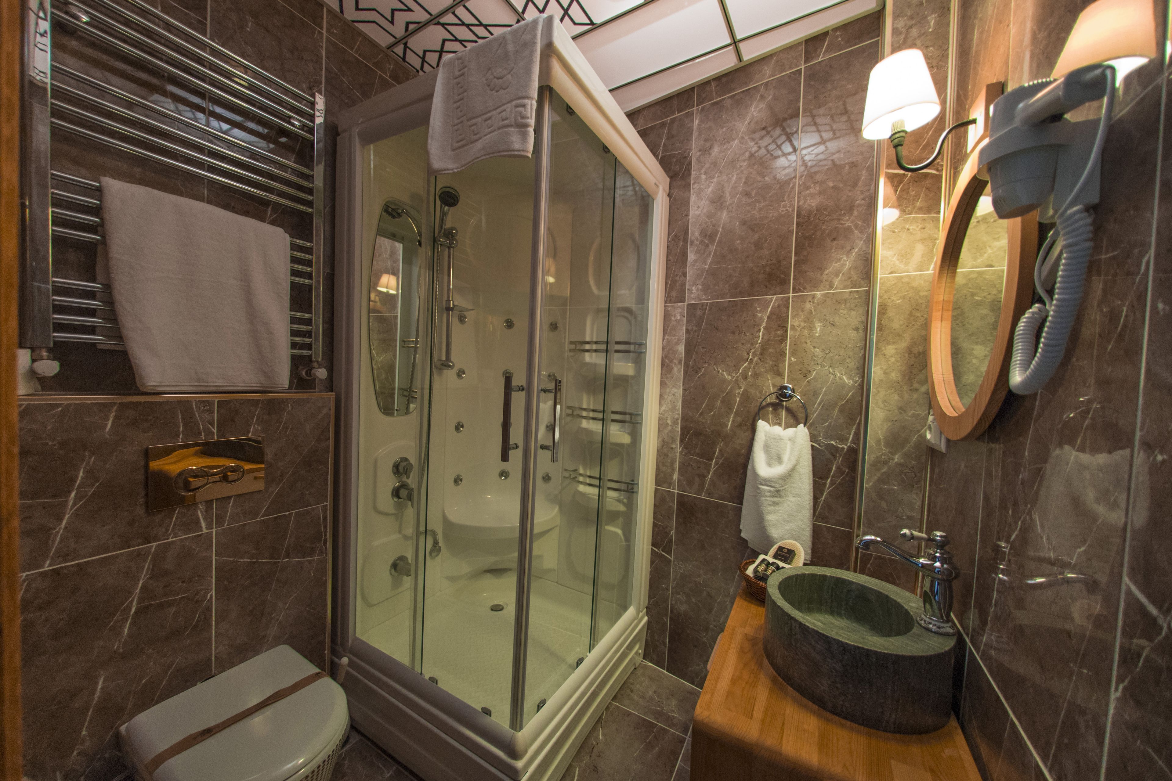 A modern bathroom with a glass-enclosed shower, a wooden vanity with a sink, and a mirror with a telephone.