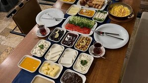 A table set with various dishes and a decorative wall with a 'B' emblem. - Bayezid Han Konak (Amasya)