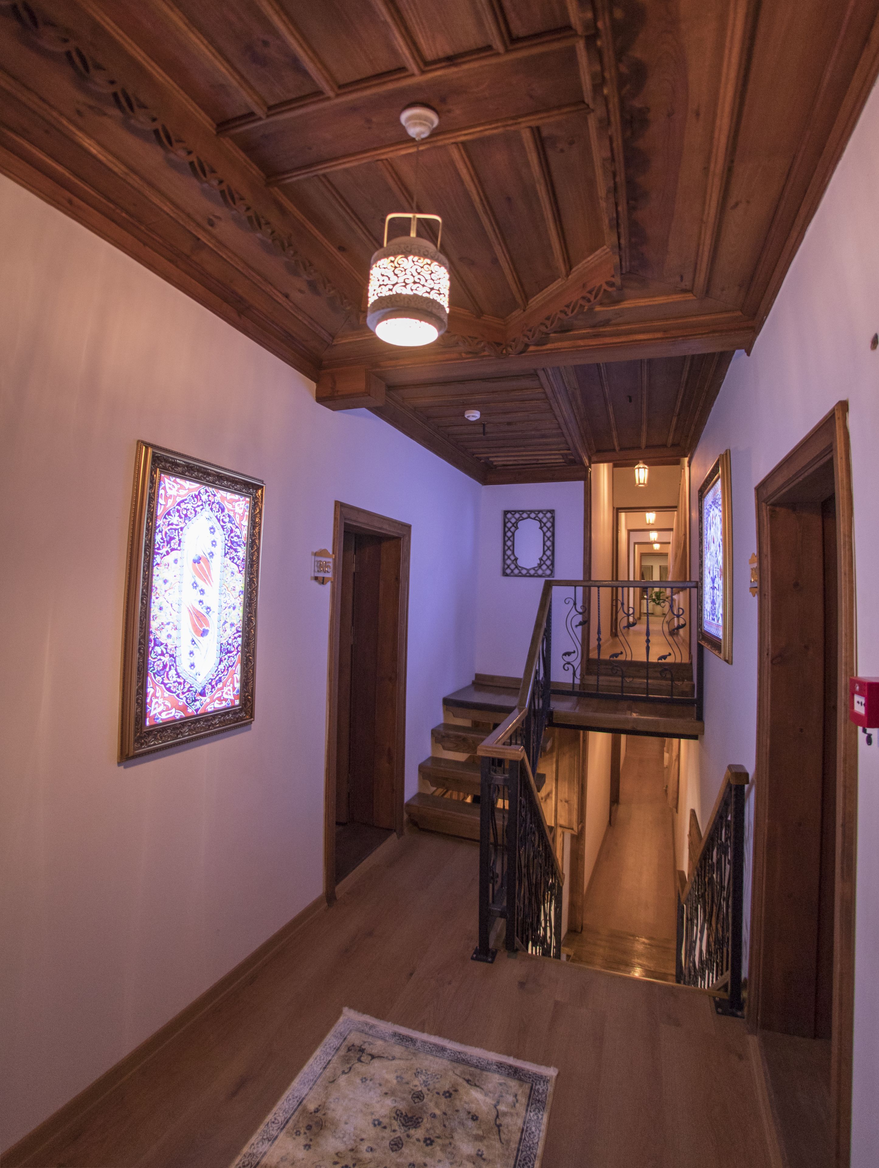 A wooden staircase with a railing, leading to a landing with a chandelier.