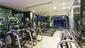 A gym with treadmills, elliptical machines, and weight benches. - The Deck Condominium by Lofty (Patong)