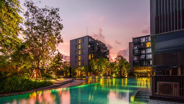 A modern building with a pool, surrounded by trees and greenery. - The Deck Condominium by Lofty (Patong)