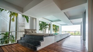 A modern interior with a wooden deck, a stone bench, and a view of palm trees. - The Quarter by Lofty (Choeng Thale)