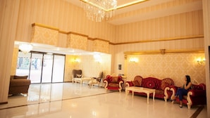 A spacious lobby with a chandelier, seating area, and a view through a glass door. - Golden Shine Hotel (Baku)