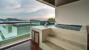 A balcony with a glass barrier, a built-in hot tub, and a view of the sea and hills. - Privilege Residences by Lofty (Patong)