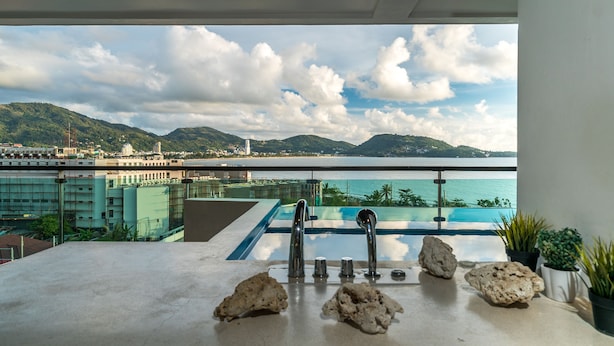 A balcony with a pool, overlooking a cityscape and mountains. - Privilege Residences by Lofty (Patong)