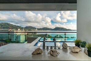 Un balcon avec piscine, offrant une vue sur le paysage urbain et les montagnes.