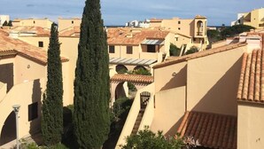 A residential area with terracotta-tiled roofs, beige buildings, and tall cypress trees. - Rev'Hotel (Leucate)