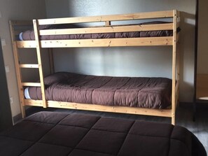 Una cama litera con dos niveles, una escalera de madera y un colchón en la cama inferior.