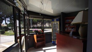A corner of a room with a wooden desk, a bookshelf, and a window with a view of the street. - Rev'Hotel (Leucate)