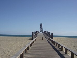 Un muelle de madera que conduce a una alta torre de estructura enrejada al final.