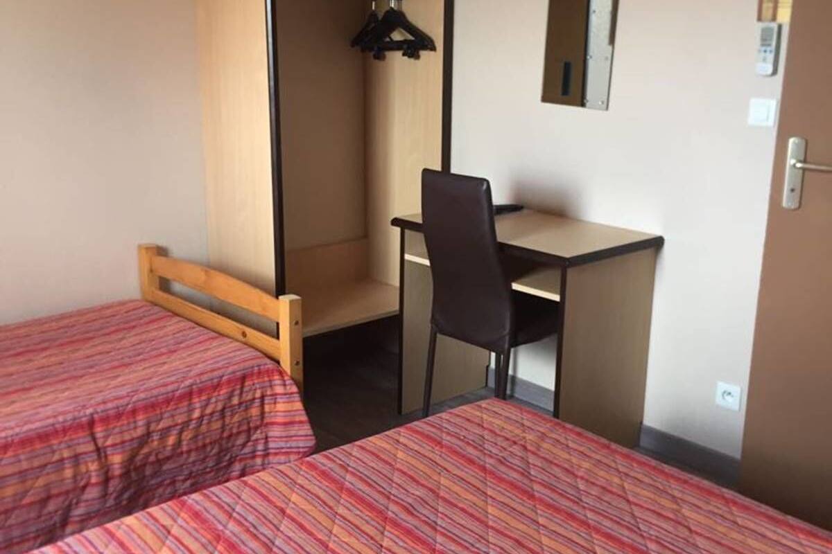 A room with two beds, a desk, and a chair.