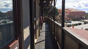 A wooden balcony with a view of a parking lot and buildings. - Rev'Hotel (Leucate)