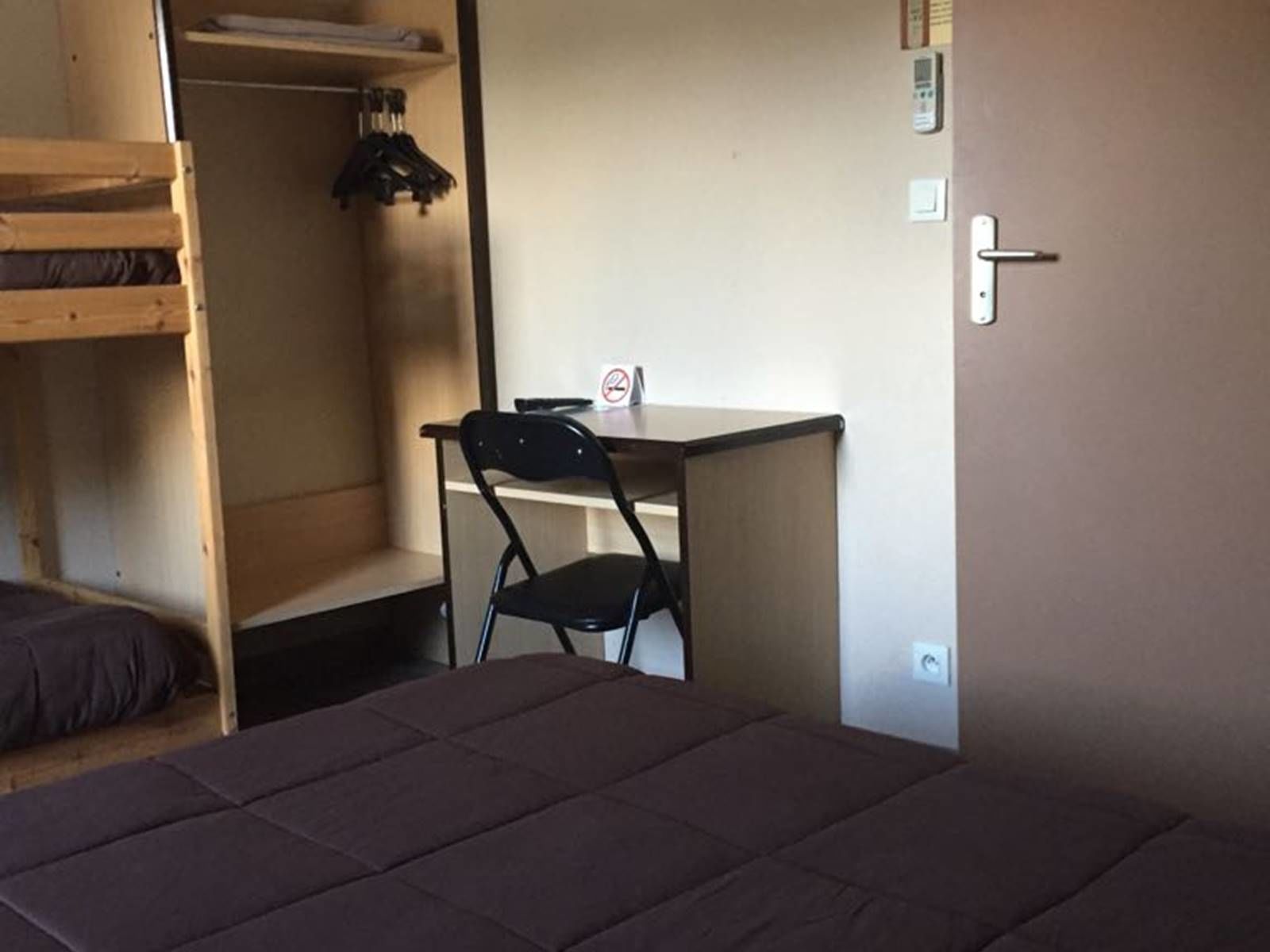 Une chambre avec un lit superposé, un bureau avec une chaise et une armoire.