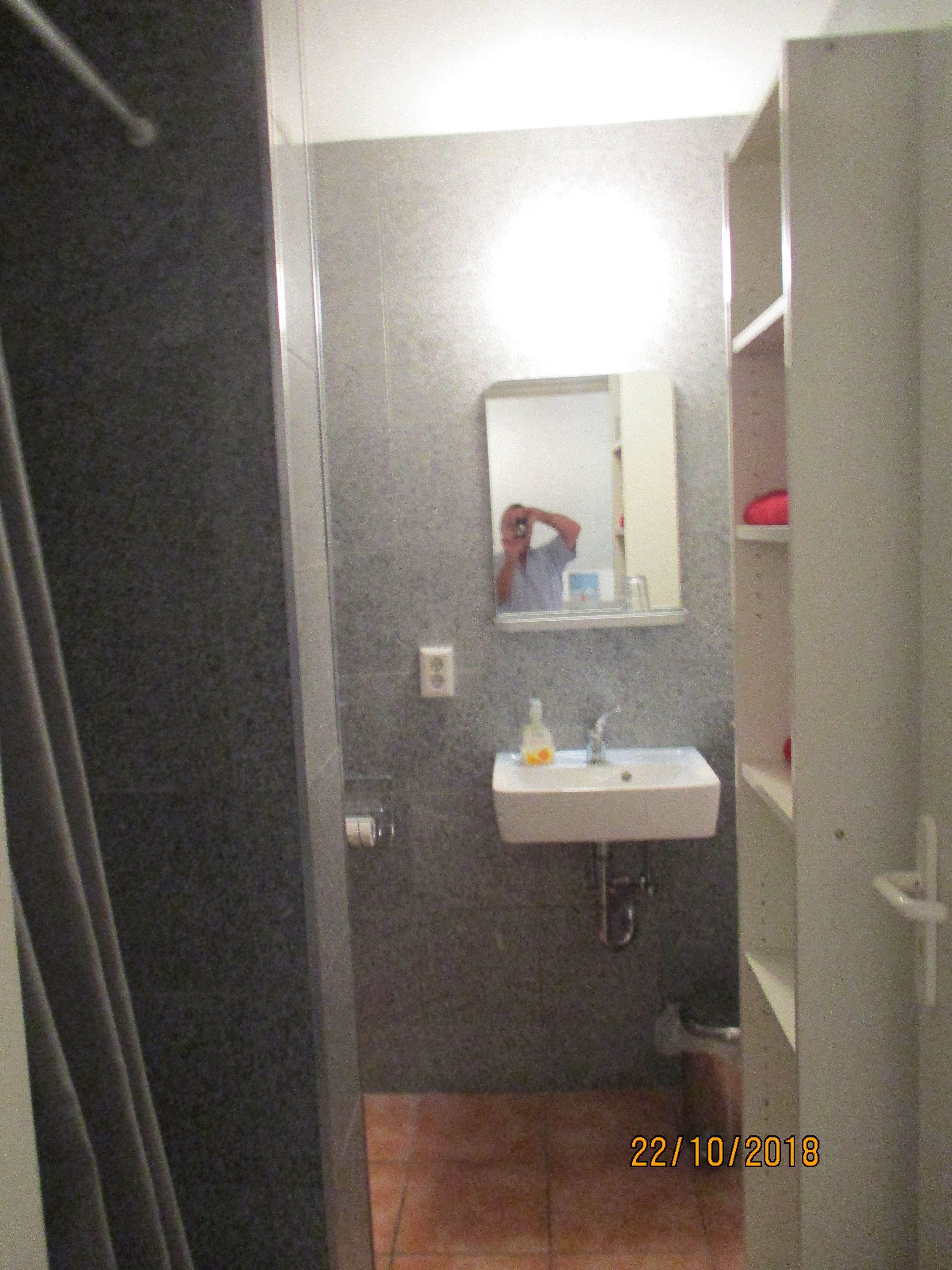 Ein Badezimmer mit Spiegel, Waschbecken und Regalen.