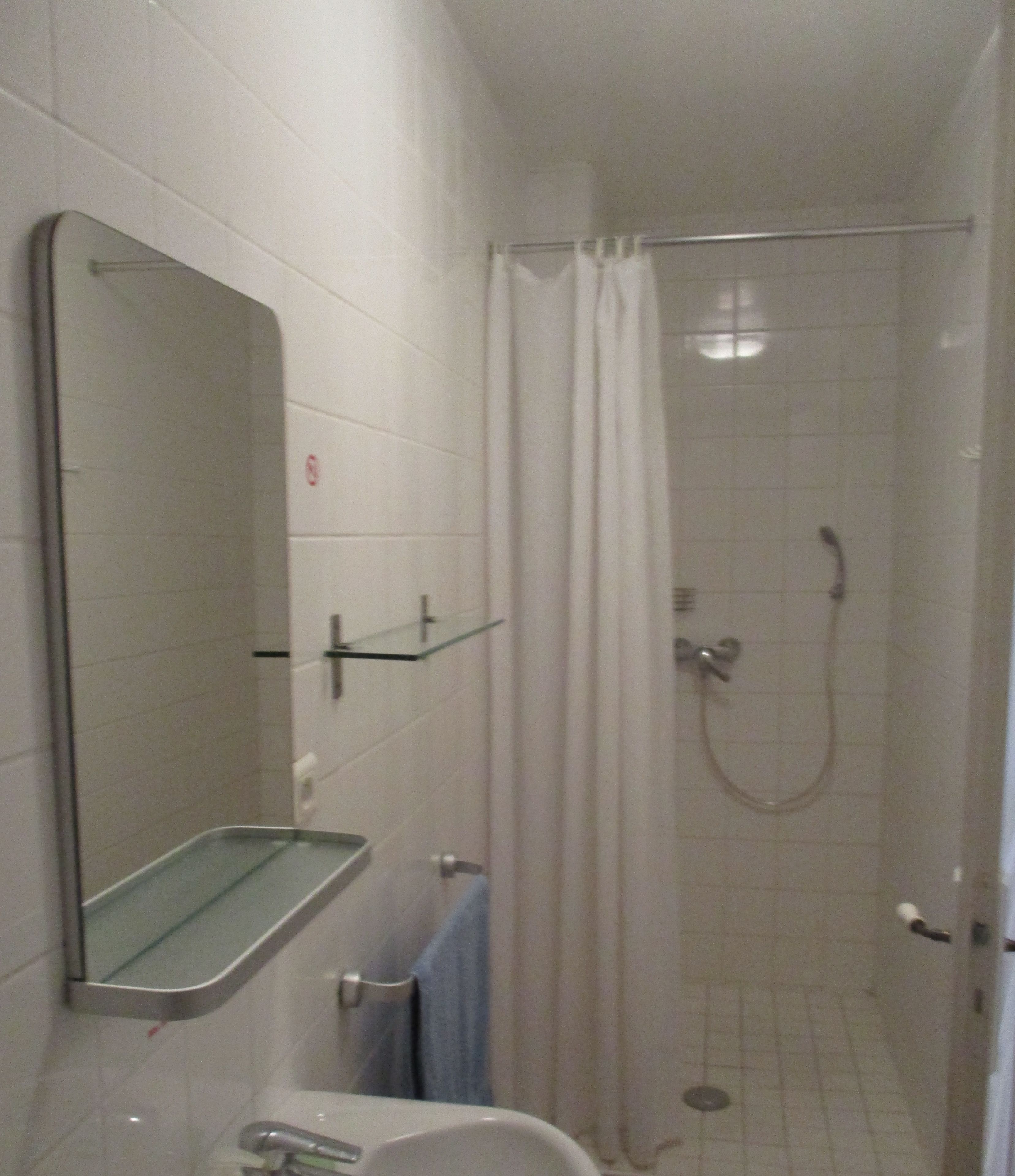 Une petite salle de bain avec une douche, un miroir et des toilettes.