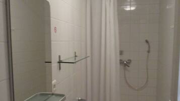 Une petite salle de bain avec une douche, un miroir et des toilettes.