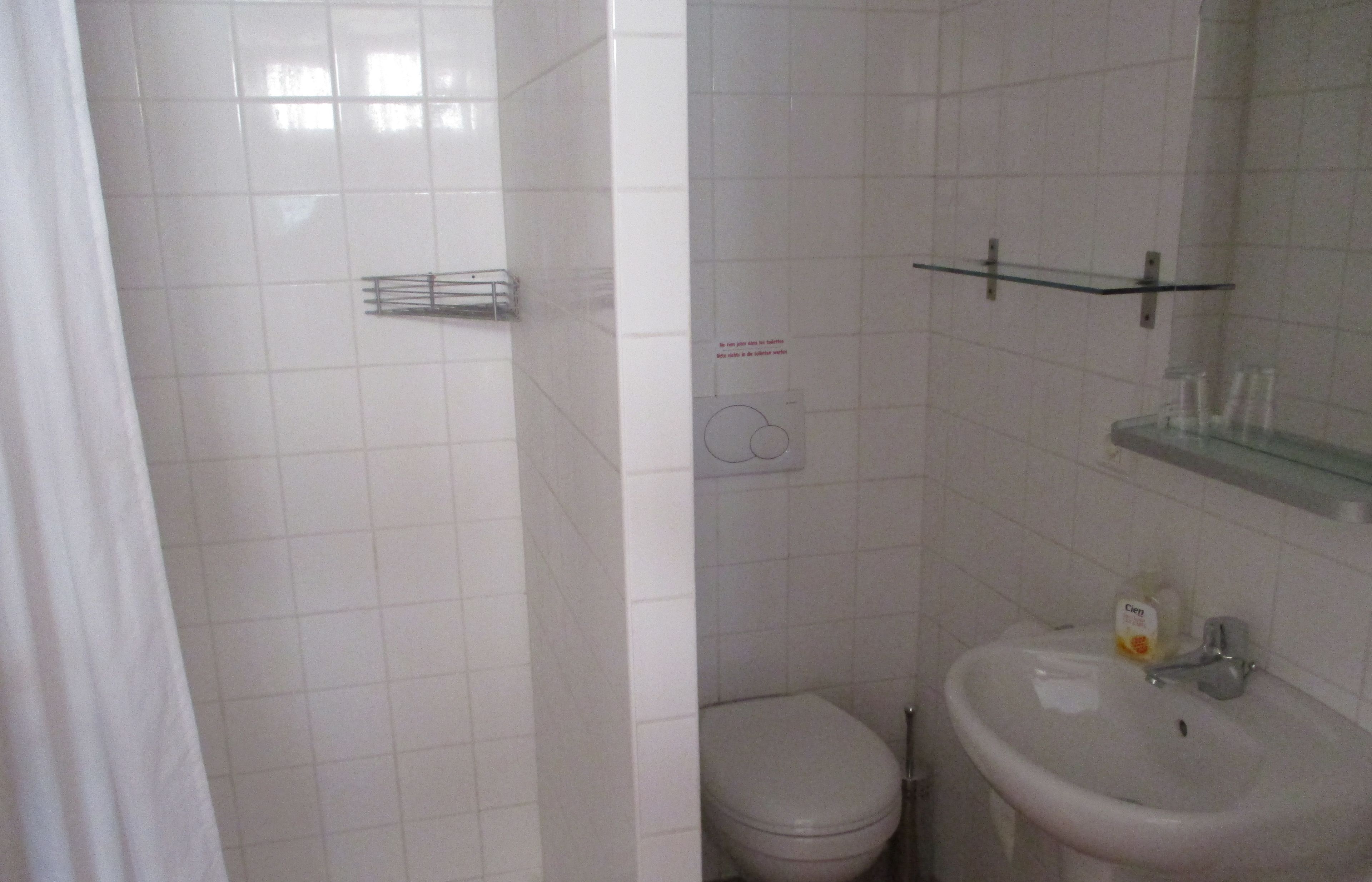 Une salle de bain comprenant des toilettes, un lavabo et un espace douche.