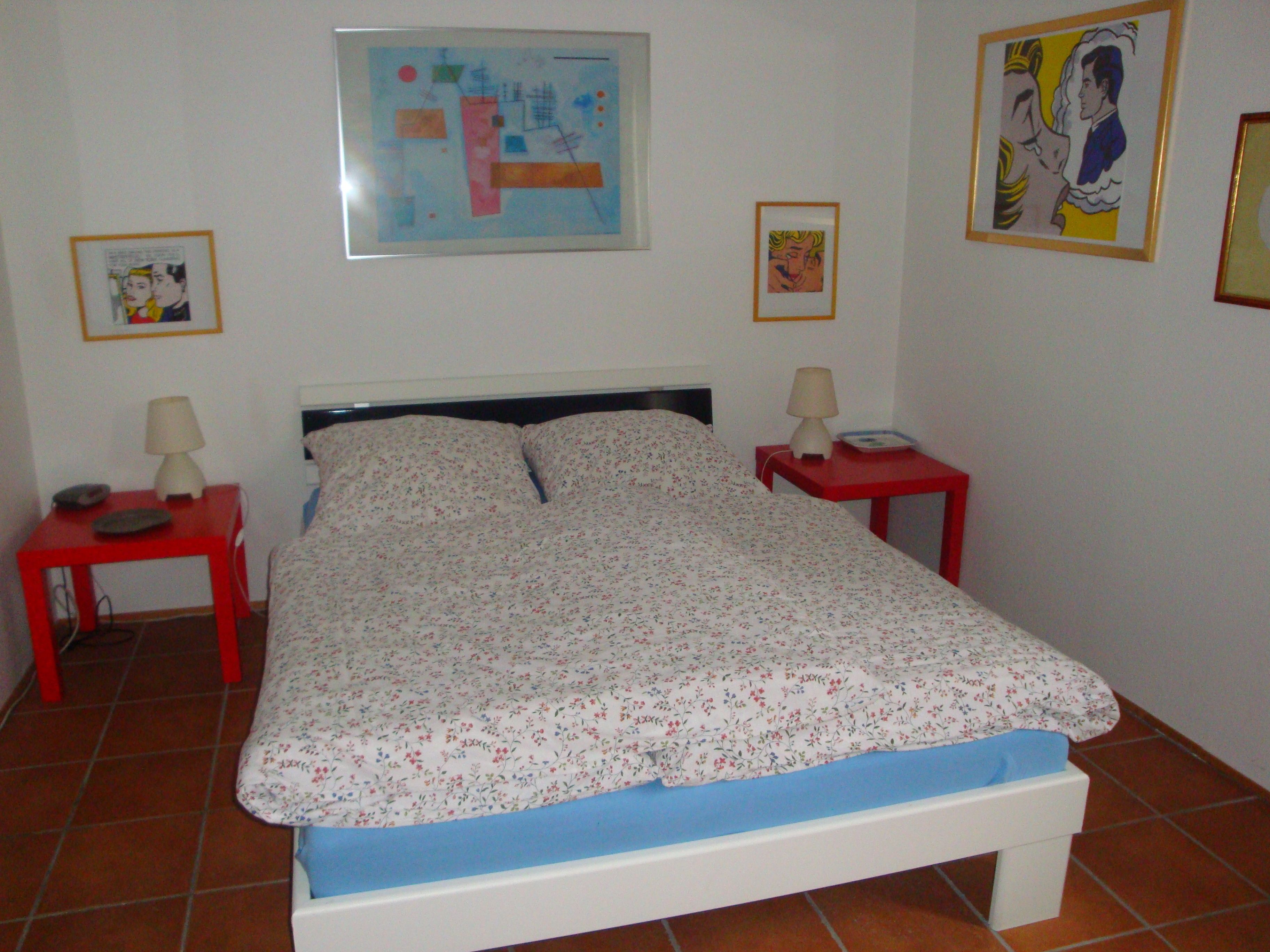 Una camera da letto con un letto, due comodini e opere d'arte alle pareti.