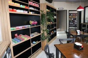A bookstore with wooden shelves stocked with books and magazines, a large potted plant, and a sign indicating a restroom.