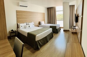 A hotel room with two beds, a desk, a chair, a TV, and a window with curtains.