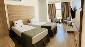 A hotel room with two beds, a TV, a desk, and a chair.