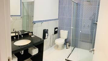 Un baño moderno con dos lavamanos, un inodoro y una ducha con cerramiento de vidrio.