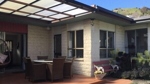 Un patio couvert avec une table et des chaises, un banc et une plante en pot.