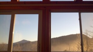 Een kamer met grote ramen die uitzicht bieden op een bergachtig landschap.