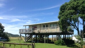 Una casa de dos pisos con balcón, escalera y patio cercado.