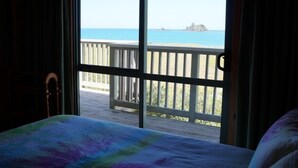 Una habitación con un gran ventanal con vistas a una playa y una terraza de madera.