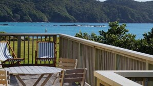Una terraza con mesa y sillas, con vista a la costa y al mar y las colinas.