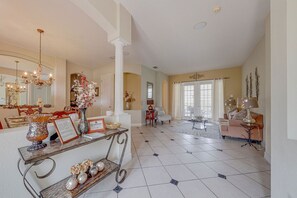 Relax in this elegantly furnished living area with a high ceiling and chandelier, featuring a sofa, armchairs, and coffee table.