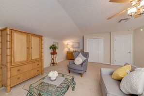 Relax in this stylish living room with a high ceiling, ceiling fan, and comfortable seating area.
